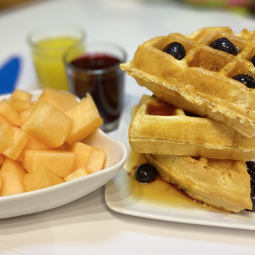 Belgian Style Waffles with Juice and Fruit on Table