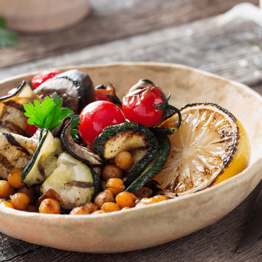 A bowl of vegetables including zucchini, cherry tomatoes and chickpeas