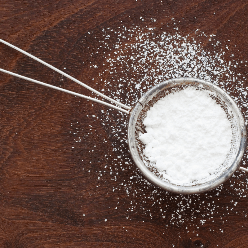 powdered sugar on a brown cutting board
