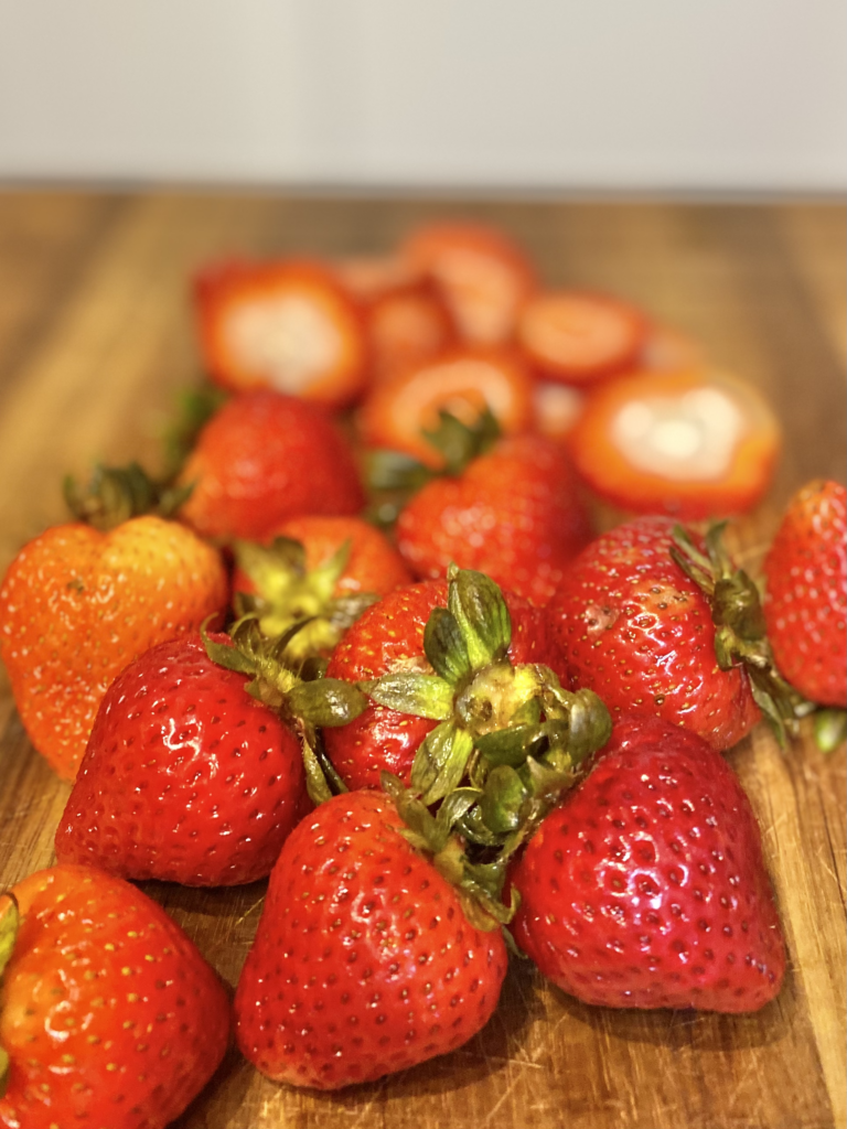 Loose strawberries on cutting board getting ready for the parfait. 