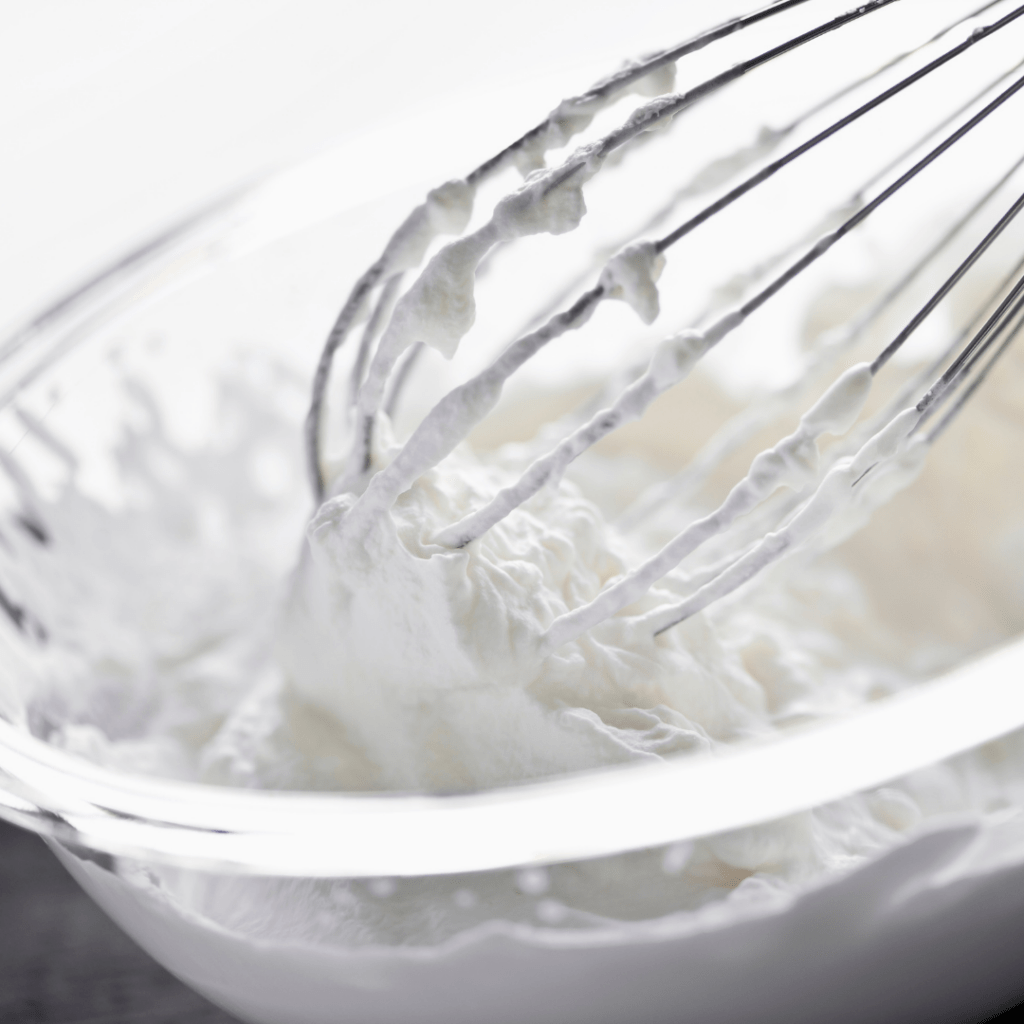 Picture of a whisk in a bowl of whipped cream for the parfait. 
