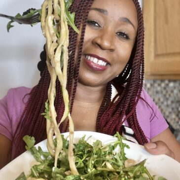 Woman holding bowl of arugula zucchini salad