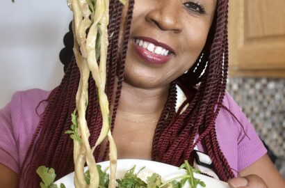 Woman holding bowl of arugula zucchini salad