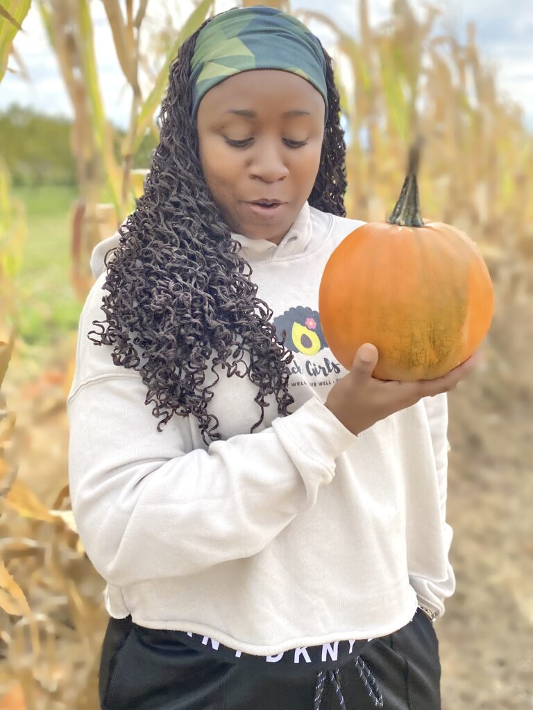 Woman is holding a pumpkin in a pumpkin patch