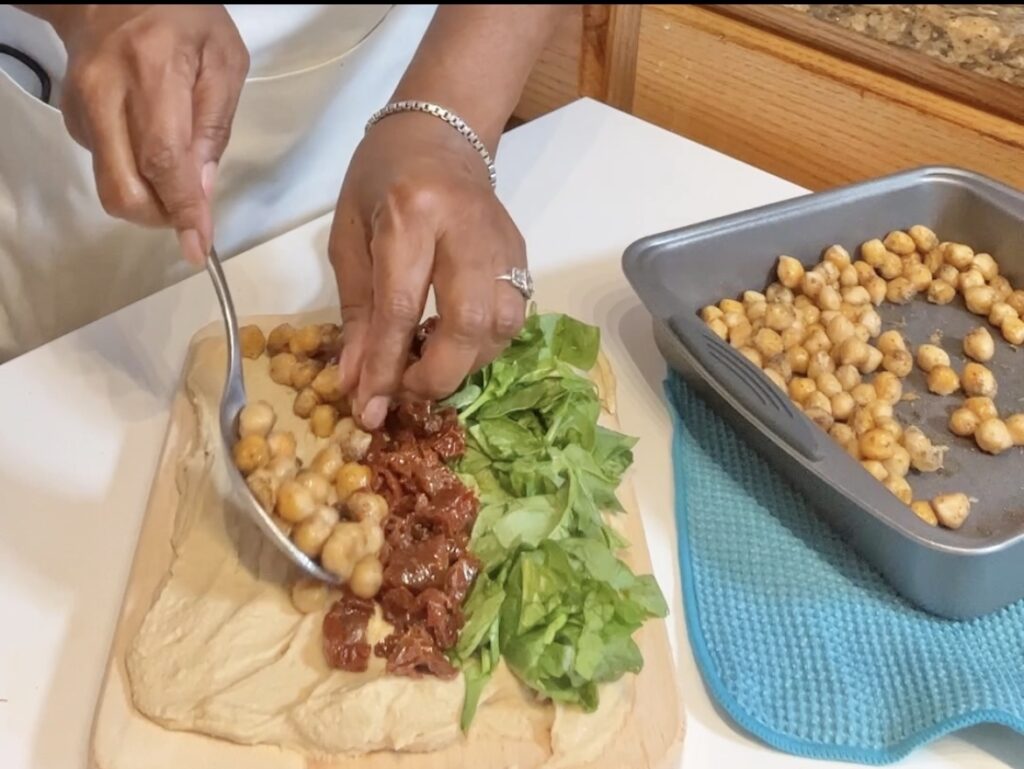 Vegan Hummus Board with hummus spinach, sun dried tomatoes and chickpeas on top