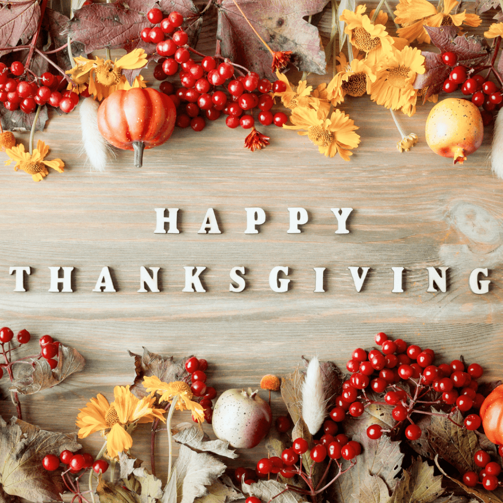 the words Happy Thanksgiving on a cutting board with berries and holiday flowers
