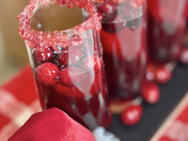 Prosecco, Cranberry Juice and Cranberries in a glass with a red sugar rim