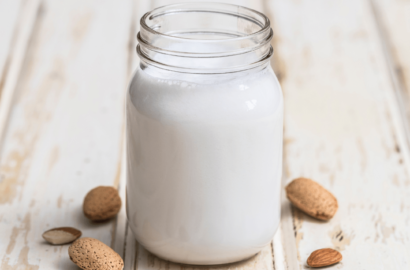 Glass of almond milk surrounded by almonds