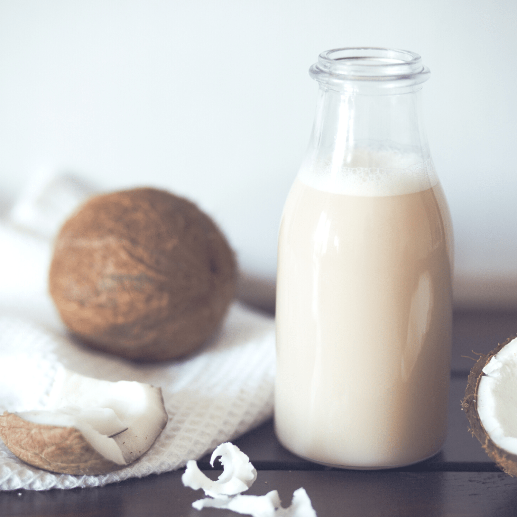 A bottle of plant-based mylk surrounded by coconuts