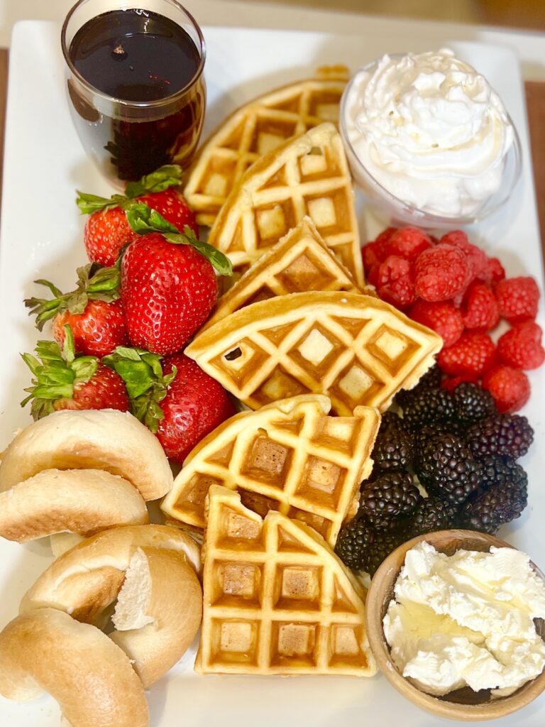 Completed breakfast board with fruit, waffles and bagels