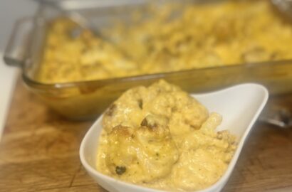 Bowl of cauliflower "mac" and cheese in front of a full dish of cauliflower "mac" and cheese