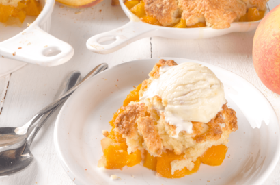 Plate of peach cobbler with a scoop of ice cream on top