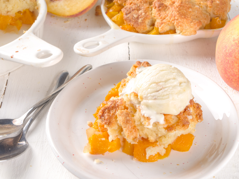 Plate of peach cobbler with a scoop of ice cream on top