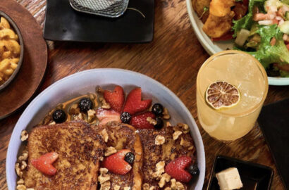 A table with french toast, a beverage, french fries and other brunch items