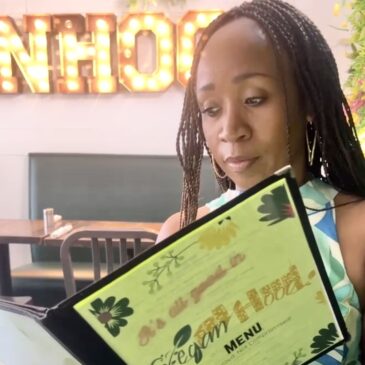 Woman at a table reading the Veganhood menu