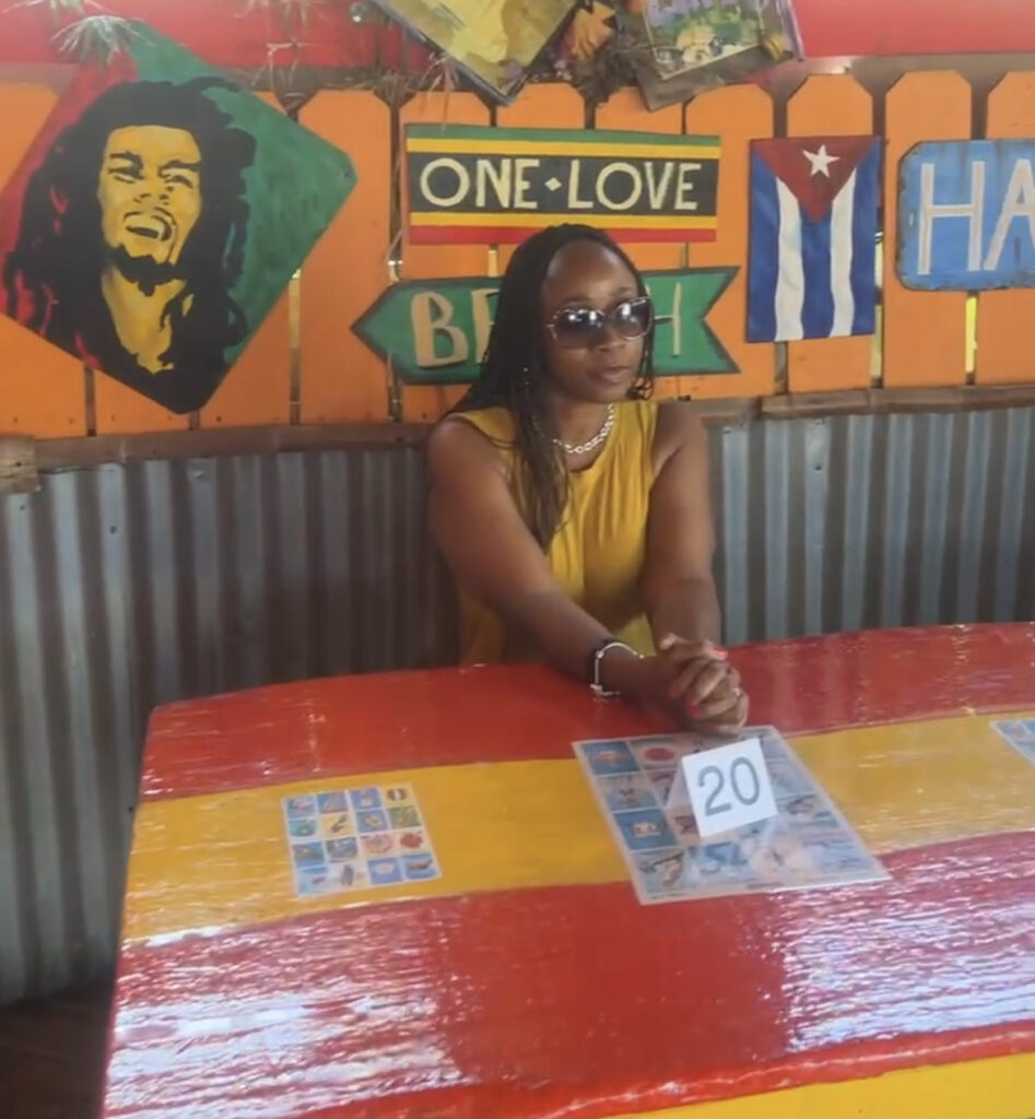 Woman in front of decorative wall inside of Cha Cha Chicken featuring Bob Marley