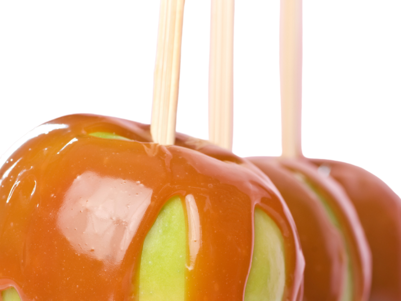 Green apples on a stick dripping with Caramel Sauce