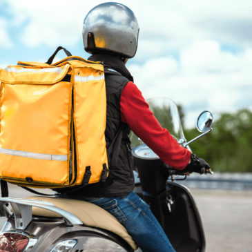 Food delivery guy on motorcycle with helmut carrying a food backpack