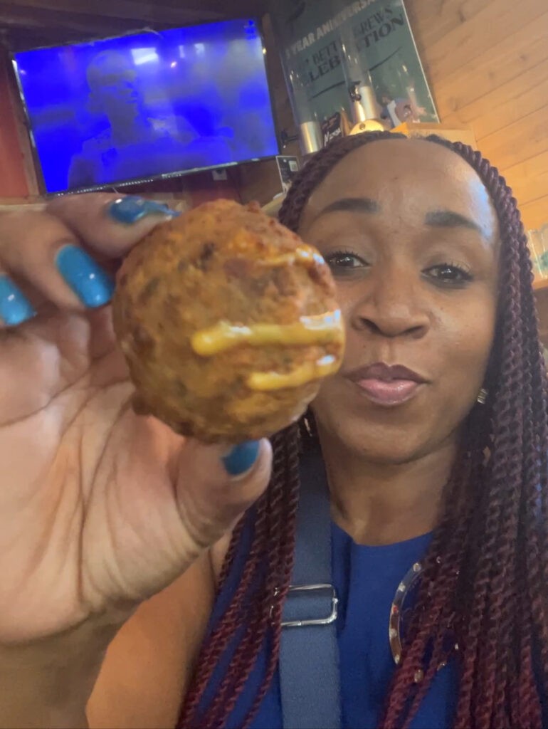 woman with boudin ball from Mo Betta Brews one of the vegan restaurants in this blog post