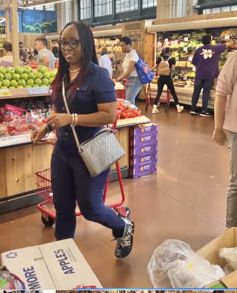 Woman in blue jumpsuit, grocery shopping in produce section at Trader Joes