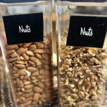 Nuts in tall, clear pantry storage containers. Almonds on the left and walnuts on the right.