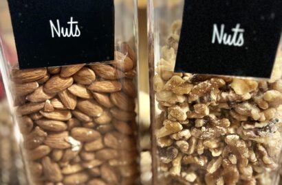 Nuts in tall, clear pantry storage containers. Almonds on the left and walnuts on the right.